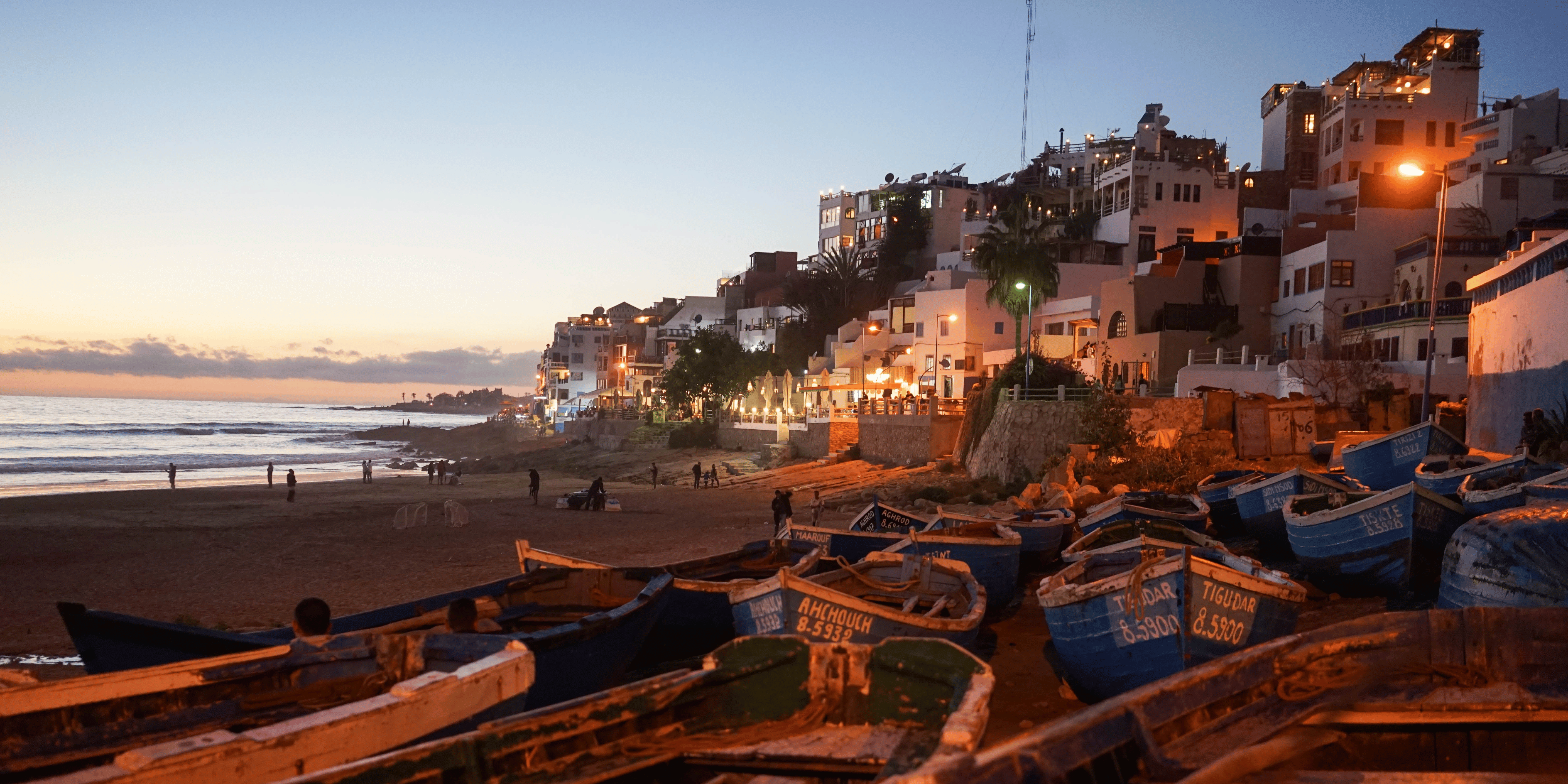 Stunning coastal view of Taghazout, highlighting its sandy beaches, clear blue waters, and surfers catching waves.